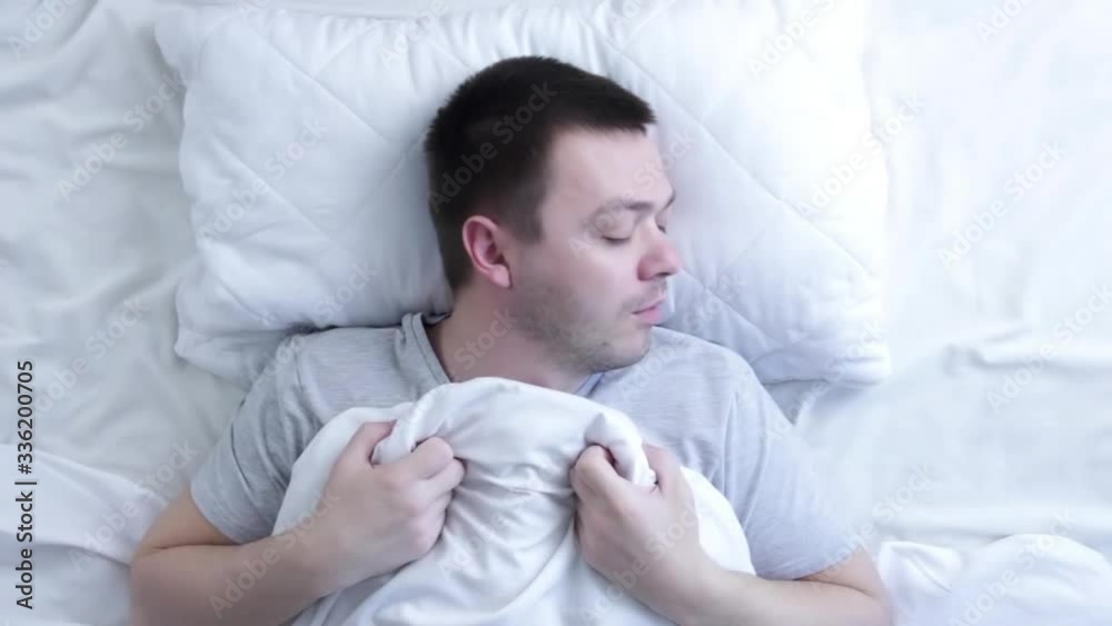 Attractive man with a beard sleeping in the bed at home. Top view of young man is sleeping in the bed. Concept of rest and sleep Attractive man with a beard sleeping in the bed at home. Top view of young man is sleeping in the bed. Concept of rest and sleep