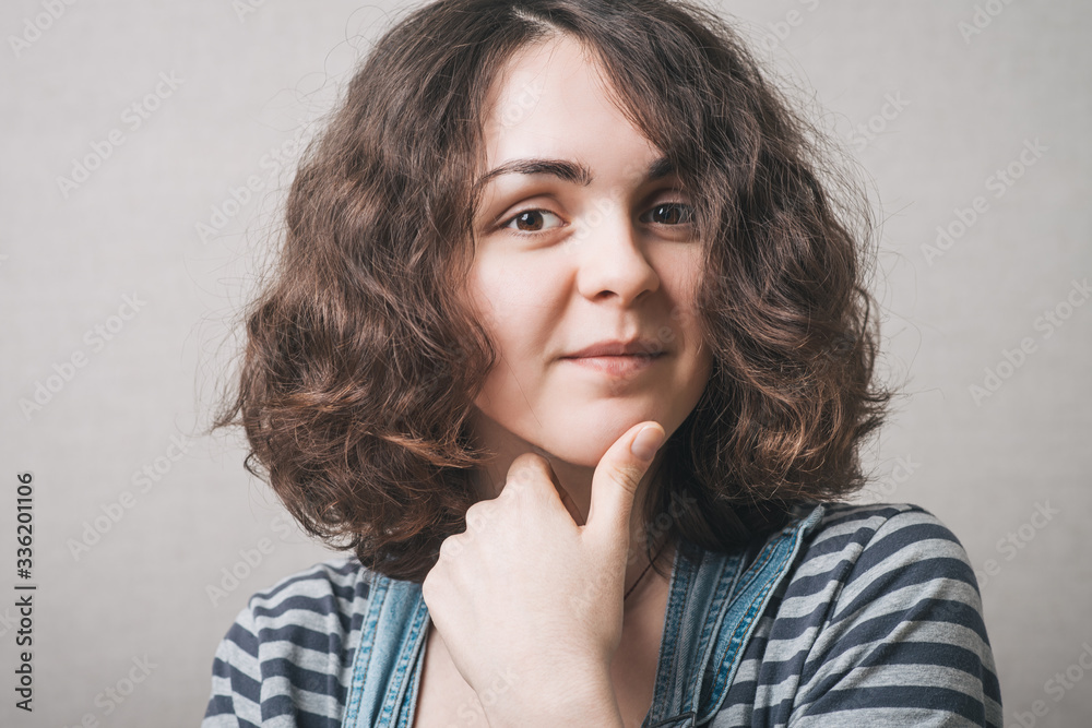 Woman thinking with hand on chin. On a gray background. Woman thinking with hand on chin. On a gray background.