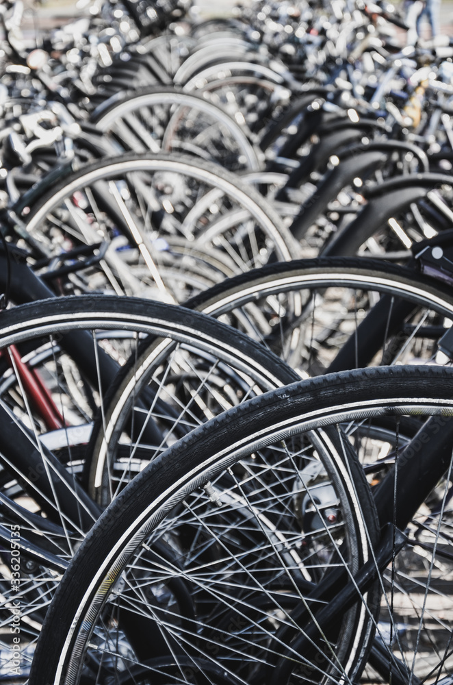 Detail of the wheels of parked bikes in Venlo, Netherlands. Some of the blurred, selective focus. Close up vertical photo with filter. Dutch bicycle parking. City biking