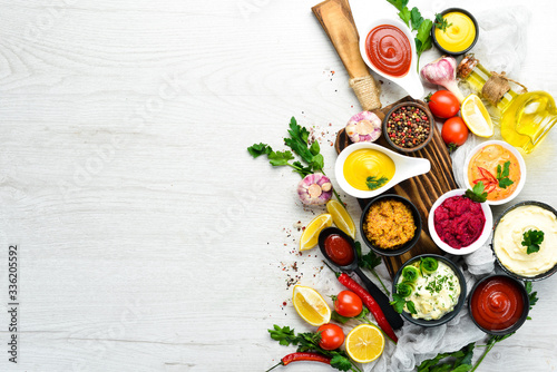 Slika na platnu Set of sauces and spices on white wooden background. Top view.