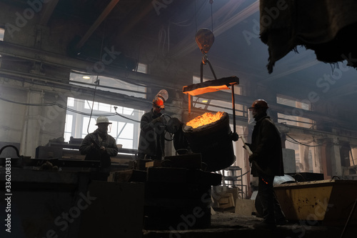 Men casting metal in grungy workshop
