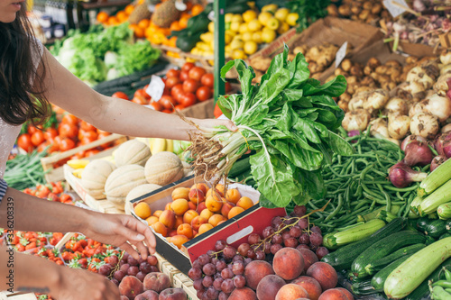 Unrecognizable female friends shopping vegetables on a market