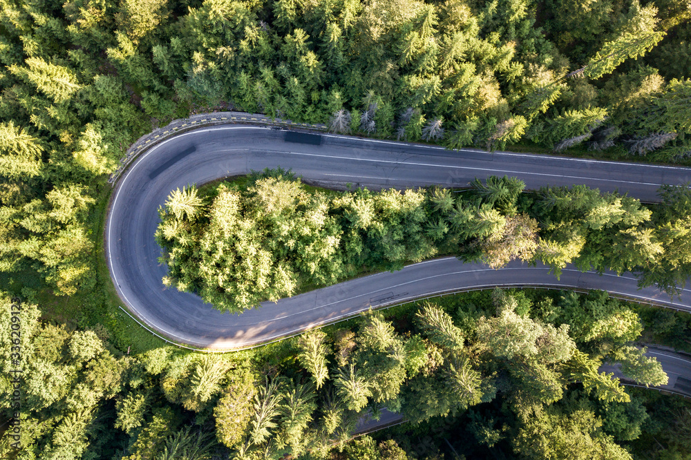 Aerial view of winding road in high mountain pass trough dense green pine woods. Aerial view of winding road in high mountain pass trough dense green pine woods.
