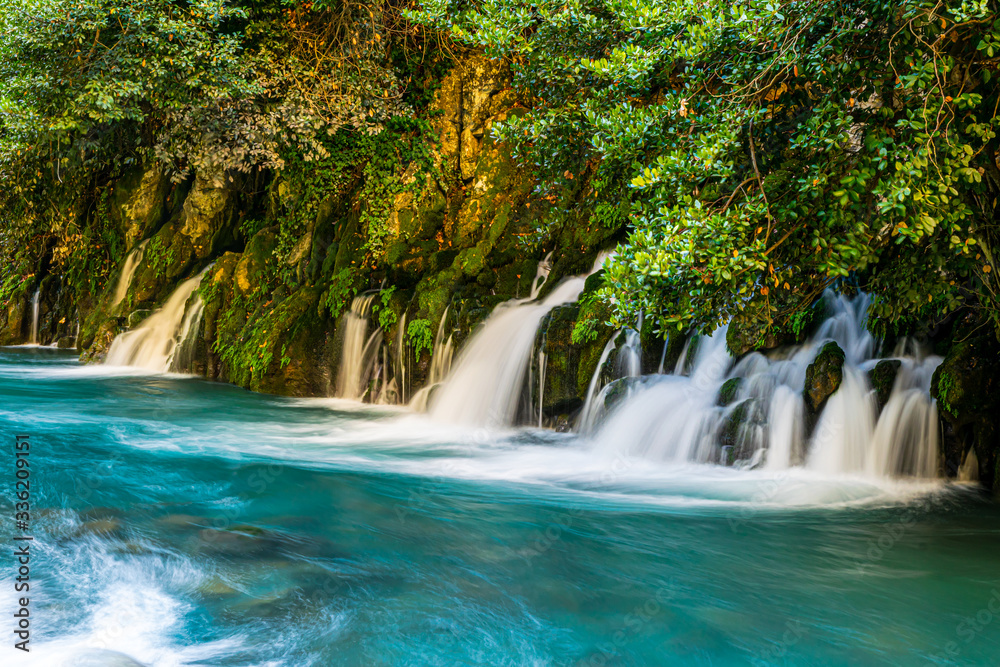 Obraz premium Karasu falls blue water current with rocks and green nature around and fence on the left side. Undiscovered beauty of Turey. Travel destination.2020