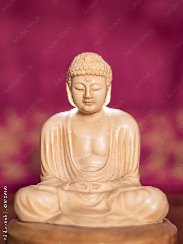 Fototapeta premium Statuette of Gautama Buddha in light marble in a prayer position