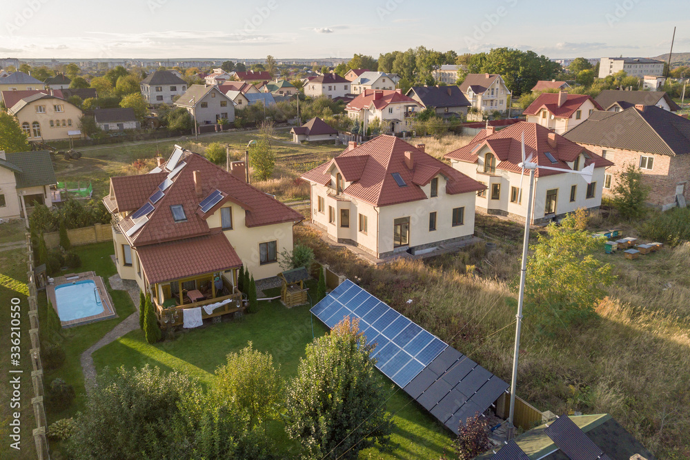 Aerial view of a residential private house with solar panels on roof and wind generator turbine. Aerial view of a residential private house with solar panels on roof and wind generator turbine.