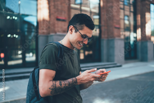 Fotografie Happy cheerful male traveller in spectacles installing application for online ca