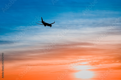 Large plane flies in the evening sunset sky, dramatic painted sky and airplane silhouette with clouds over Lisbon in Portugal. © SValeriia