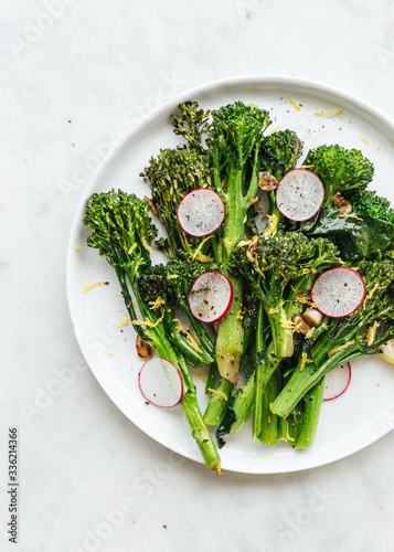 Plate of stir-fried broccolini with slice radish and lemon zest