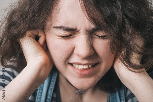 Young woman with its hands covering his ears not to hear noise.