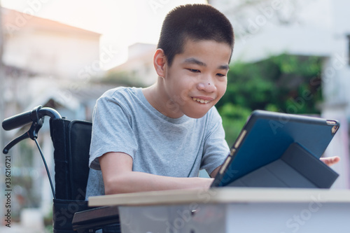 Disabled child on wheelchair happy time to use a tablet in the house, Study and Work at home for safety from covid 19, Life in the education age of special need kid, Happy disability boy concept. photo