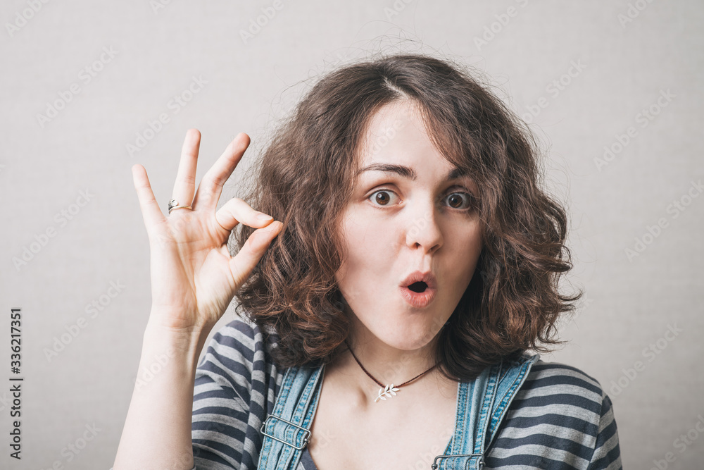 Girl shows everything is OK, dressed in overalls