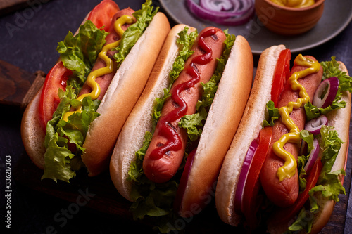 Hot dog with pickles and lettuce on blue concrete background.