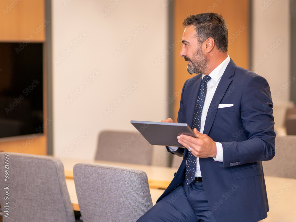 A smart-suited, bespectacled and saccid boss who controls both instant data and social media using his tablet as he wanders through the office A smart-suited, bespectacled and saccid boss who controls both instant data and social media using his tablet as he wanders through the office