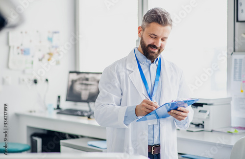 Dentist with clipboard in modern dental surgery, writing.