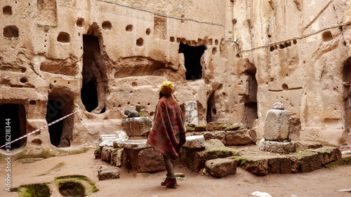 Woman alone at ancient Gumusler Monastery surrounded by old stones and ruins in Gumusler, Nigde