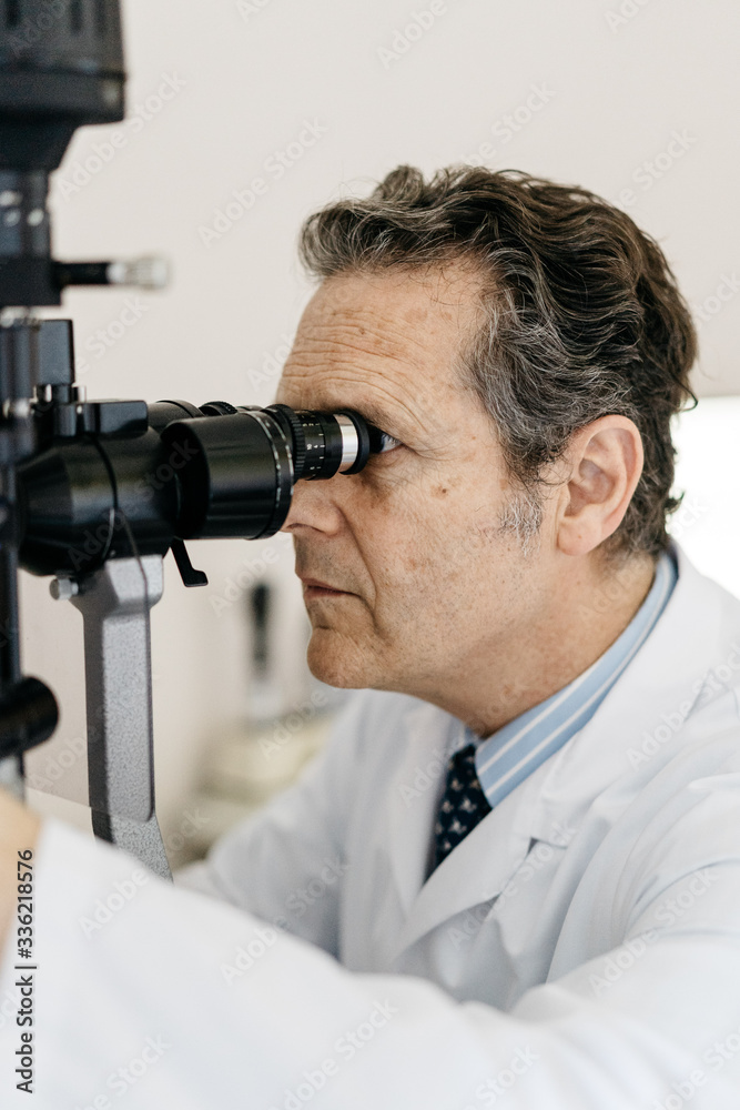 Close-up of an ophthalmologist looking through the slit lamp Close-up of an ophthalmologist looking through the slit lamp