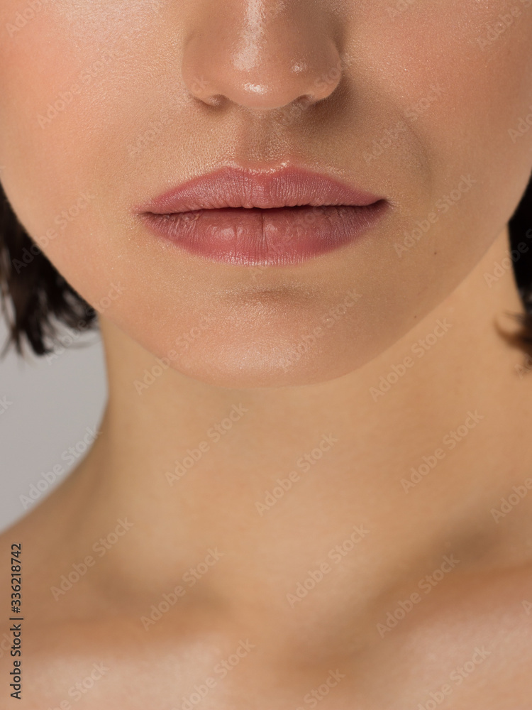 Obraz premium Close-up of woman's lips with fashion natural beige lipstick makeup. Macro sexy pale lipgloss make-up . Gentle pure skin and wavy blonde hair. Cosmetology, Spa, increase in lips. Face powder