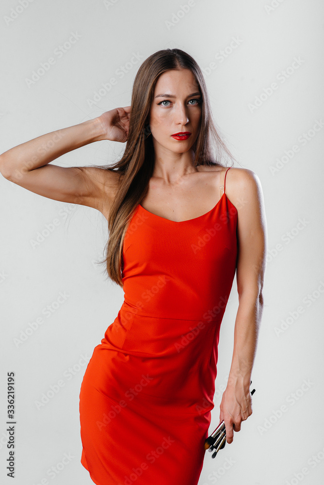 Fototapeta premium A beautiful young makeup artist poses with tassels on a white background in the Studio. Makeup