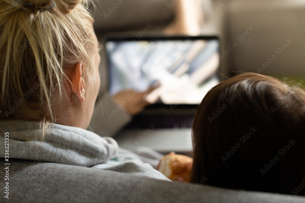 Mother and child watching tv on the couch at home; Family time Mother and child watching tv on the couch at home; Family time