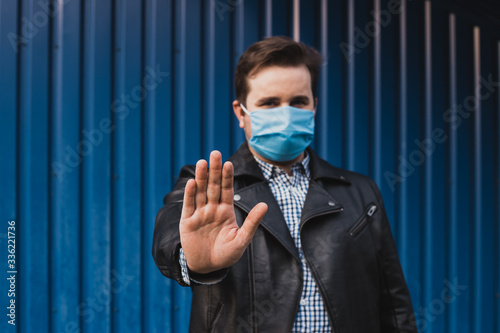 stop coronavirus. man showing gesture stop. man wears protective mask against infectious diseases and flu. health care concept. coronavirus quarantine.