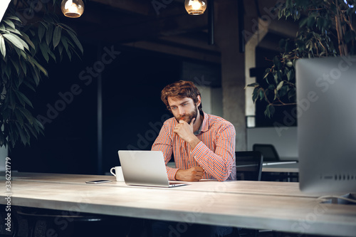 Puzzled thoughtful businessman sitting at his working table in an office. Business concept