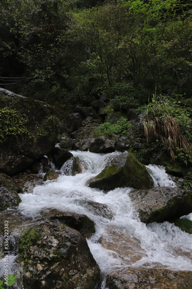Beautiful landscape of cascade falls over mossy rocks, stones cover with moss, in a Mountain in Sichuan, China Beautiful landscape of cascade falls over mossy rocks, stones cover with moss, in a Mountain in Sichuan, China