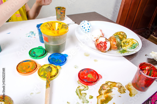 Children are preparing for Easter. Coloring eggs with brushes and multi-colored paints