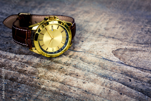 A gold wristwatch sits on a vintage wooden background photo