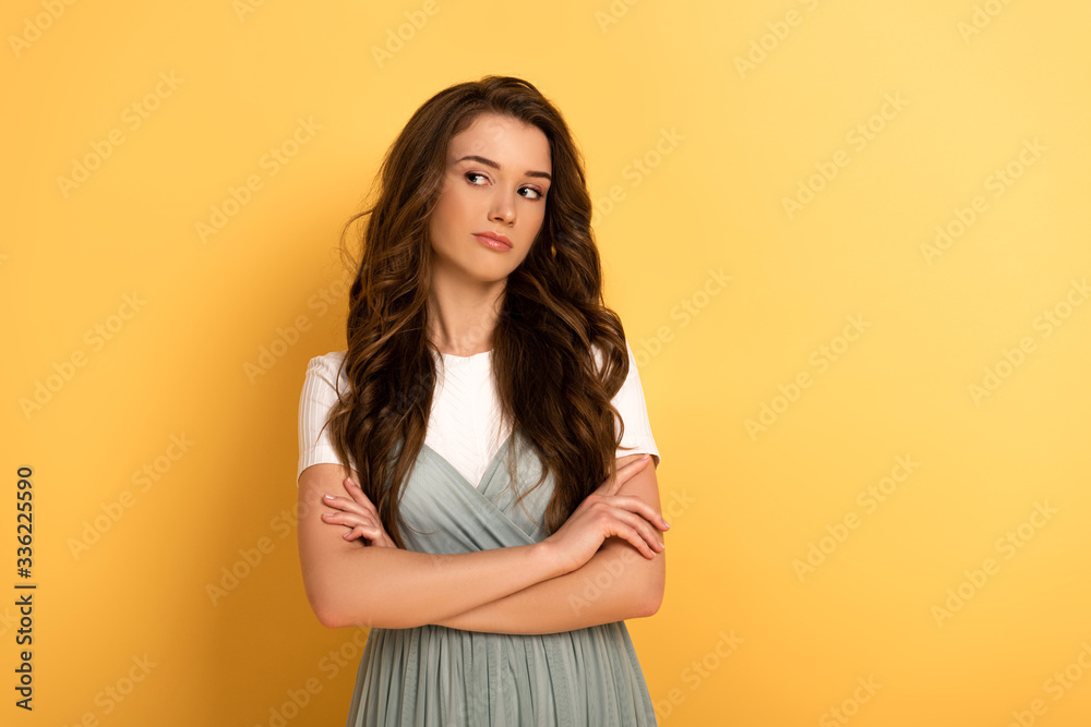 attractive thoughtful spring girl with crossed arms on yellow attractive thoughtful spring girl with crossed arms on yellow