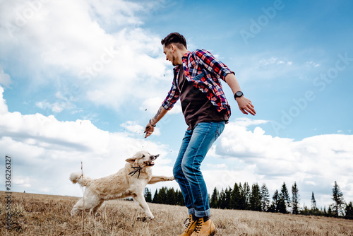 A man plays with his dog in nature