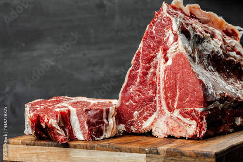 Raw T-bone steak cooking on stone table. photo