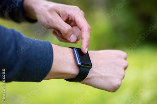 Man in nature using smartwatch app. Close-up hands