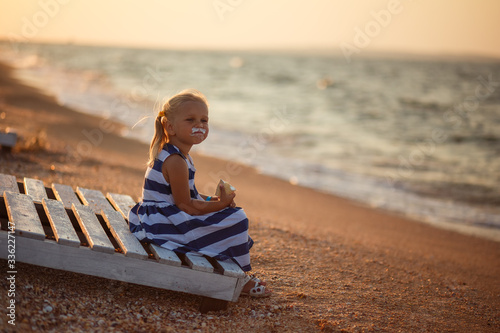 girl sitting on the beach eating ice cream, looking at the water, sunset, happiness is, childhood