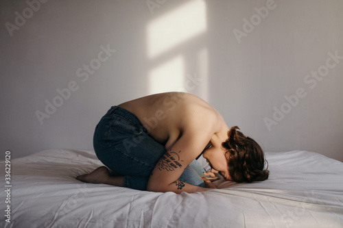 Topless overweight female praying on bed photo