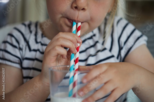 Child drinking milk through a paper straw photo