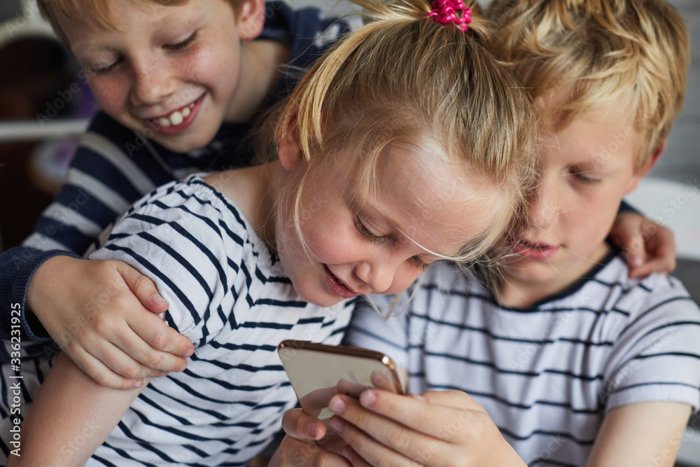 Three children using a smart phone together Three children using a smart phone together