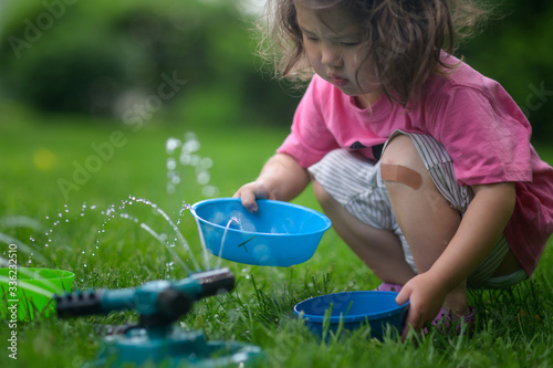 Little kid playing with sprinkler water