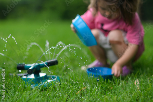 Little kid playing with sprinkler water