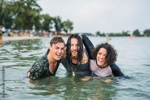 Group of wet young friends at summer festival, standing in lake.