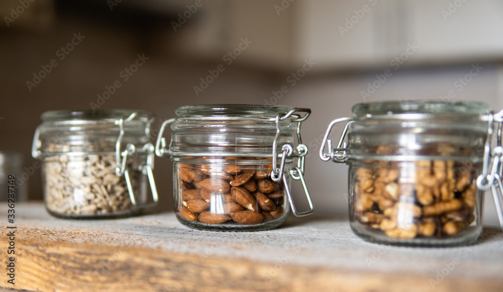 Sunflower seeds, walnut and almond in a jars which standing on a white vintage table with a kitchen on background. Nuts is a healthy vegetarian protein and nutritious food. Nuts on rustic old wood. Sunflower seeds, walnut and almond in a jars which standing on a white vintage table with a kitchen on background. Nuts is a healthy vegetarian protein and nutritious food. Nuts on rustic old wood.