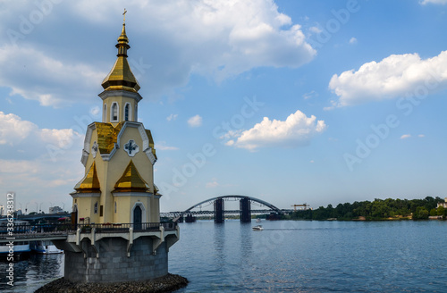 The Church of St. Nicholas on the water, a small chapel is built right into the water old embankment and Havanskyi Bridge sunny summer day. Kiev, Ukraine photo