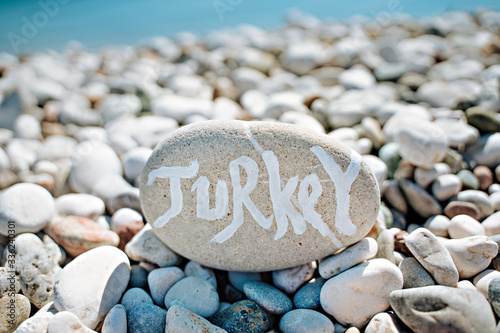 Fototapeta Naklejka Na Ścianę i Meble -  stones on the beach with a blue sea and the inscription turkey