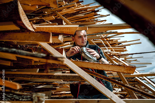 Worker man at a sawmill and a stack of wood