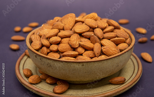 Pile of roasted almonds in a wooden pot close up view