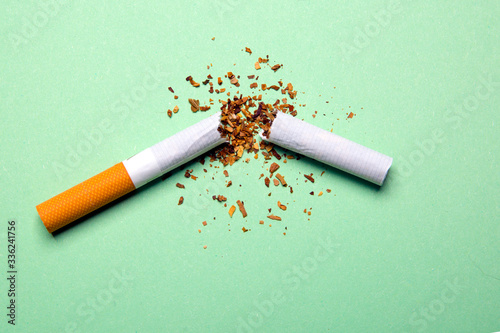 Broken cigarette on a green background, tobacco