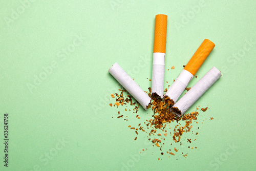 Two broken cigarettes on a green background
