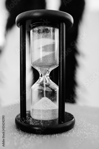 white sand hourglass in brown wood on table