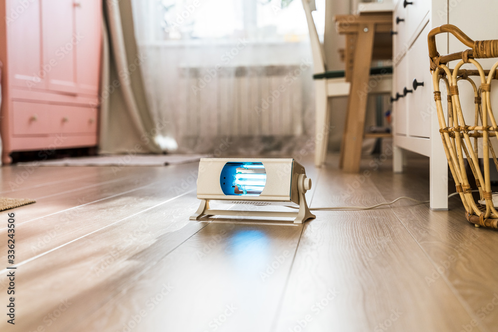 Naklejka premium A working ultraviolet lamp in the background of a children's room. Protecting and cleaning rooms from bacteria and viruses in the context of the coronavirus pandemic. Child Health Care