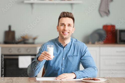 Young man drinking milk in kitchen